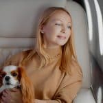 A woman sits on a private jet with her pet dog