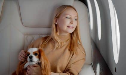A woman sits on a private jet with her pet dog
