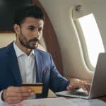 A man on a private jet holding a credit card