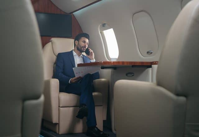 A businessman makes a call on a large business jet flight