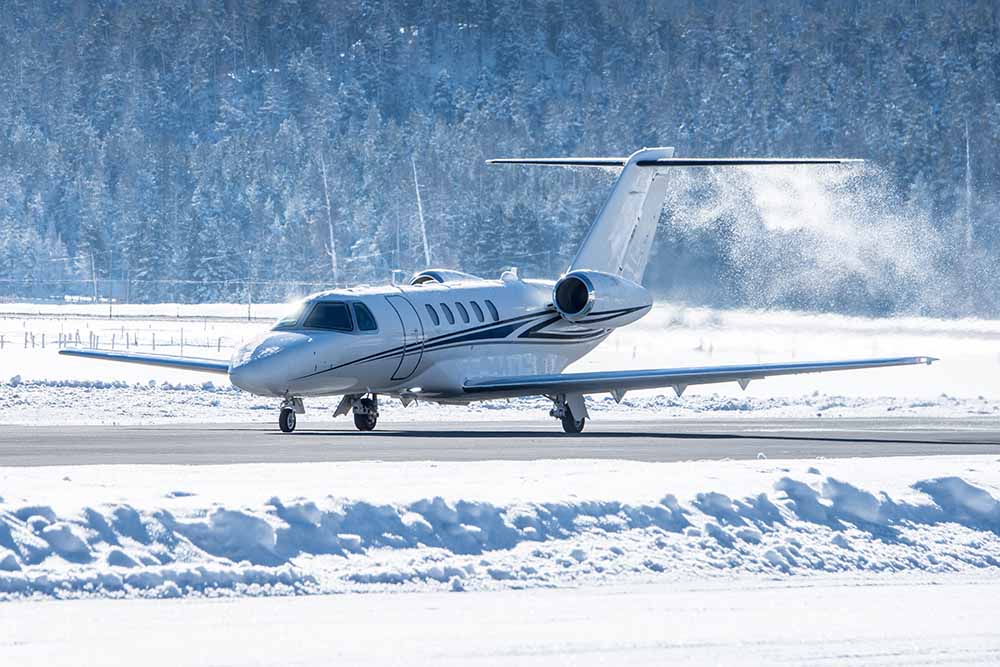 A private jet takes off from a snow-covered airfield