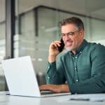 A private jet charter broker talks on the phone with a client while in their office.