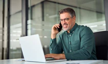 A private jet charter broker talks on the phone with a client while in their office.