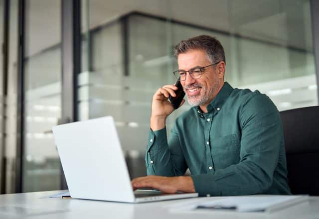 A private jet charter broker talks on the phone with a client while in their office.