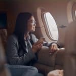 A happy woman looking out the window on a private jet