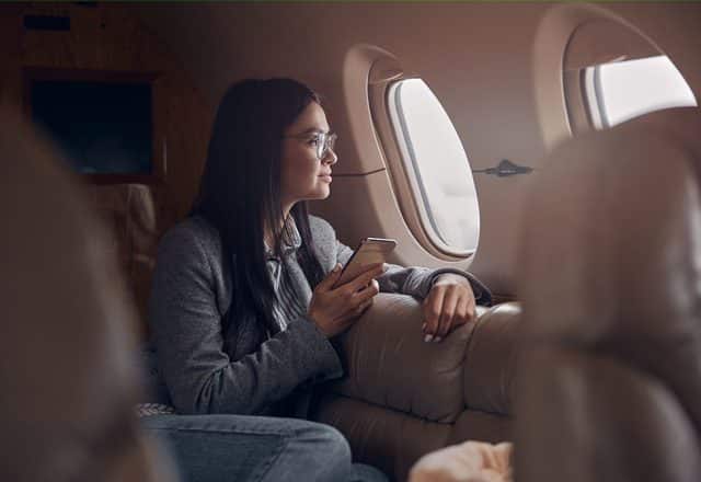 A happy woman looking out the window on a private jet