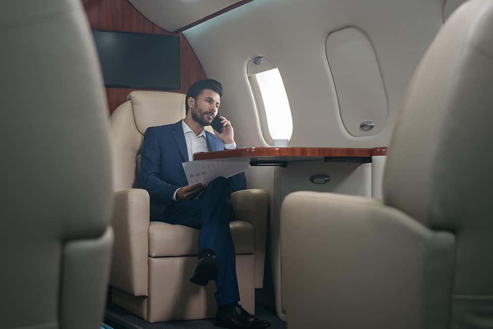 A man on his phone sitting on a private jet