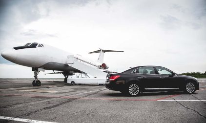 A car on the tarmac next to a private jet