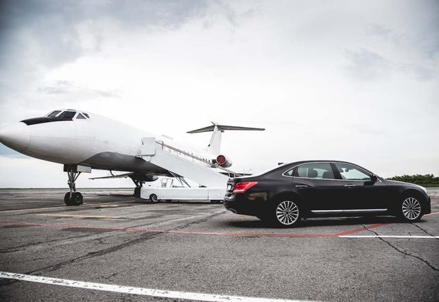 A car on the tarmac next to a private jet