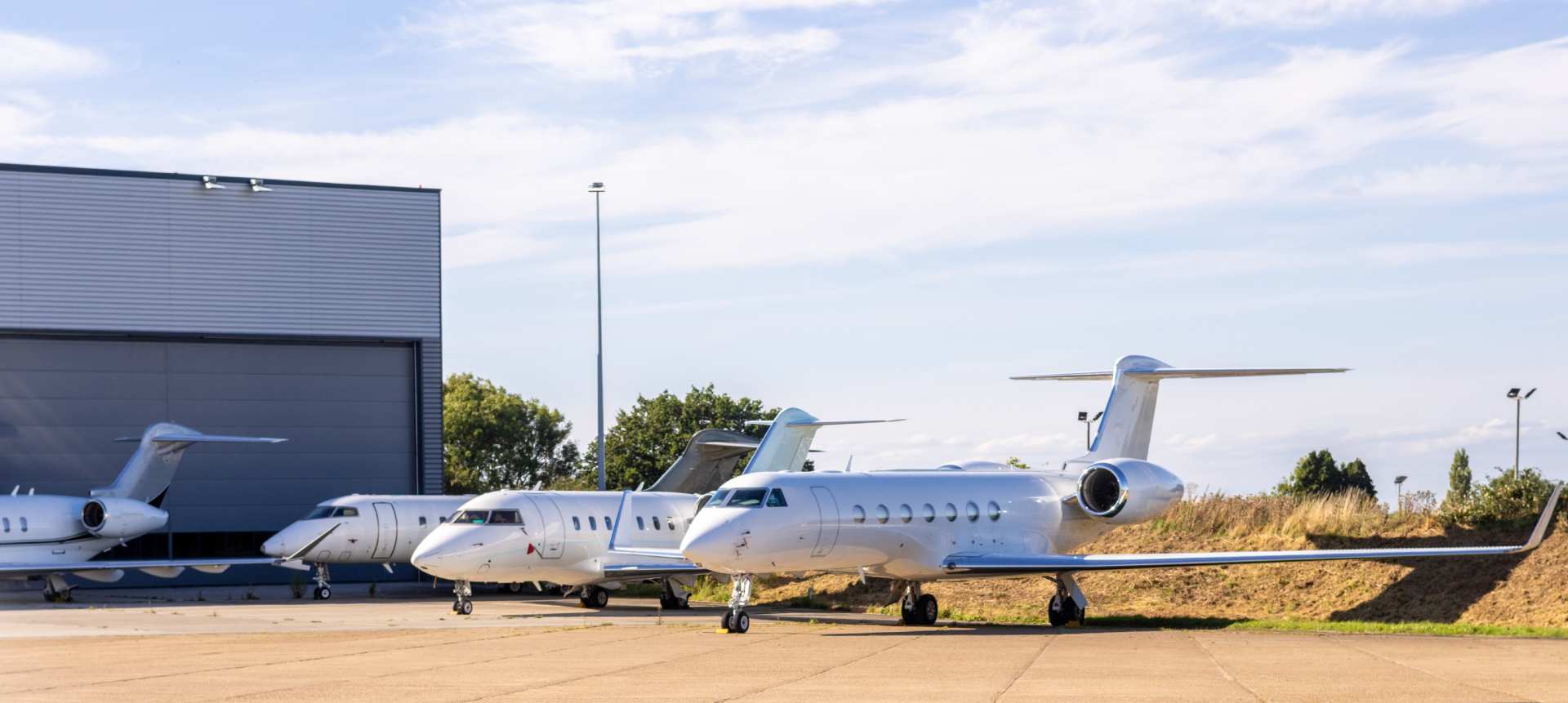 Private jets sit outside of a hangar.