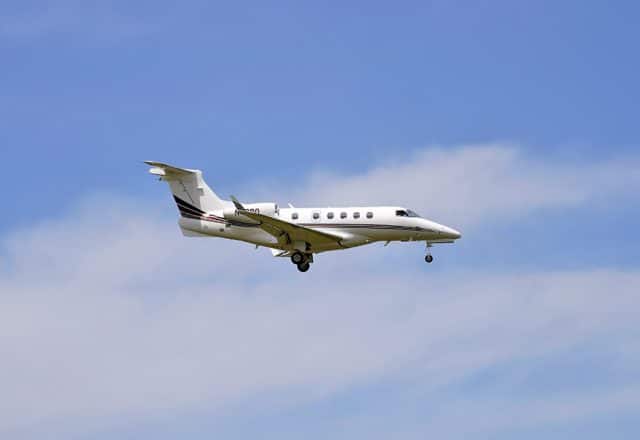 A private jet with wheels down approaches a runway.