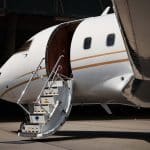 A private jet sits in a hanger with its stairs extended.