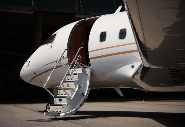 A private jet sits in a hanger with its stairs extended.