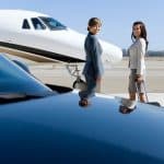 Two travelers approach a private jet on the runway.